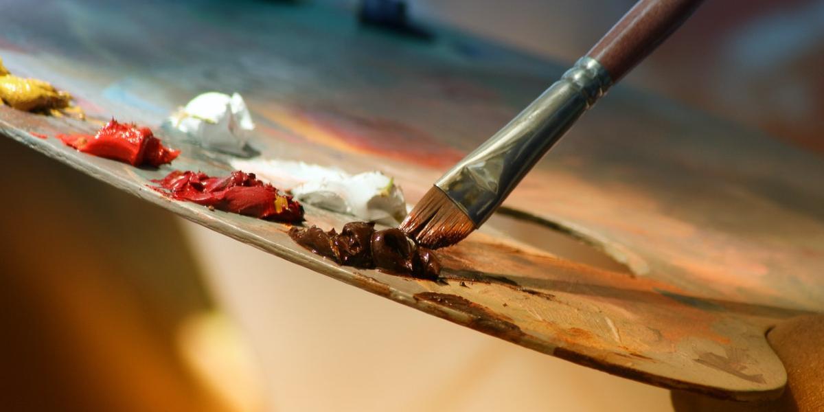 Close up of paintbrush being used on wooden pallet.