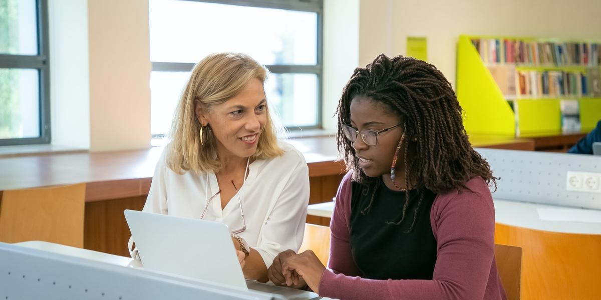 Two woman talking and learning in library.