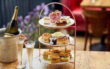 Afternoon tea arranged on table with glasses of sparkling wine inside Bistrot Pierre.