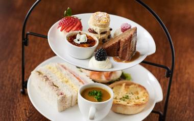 Desserts and savoury snacks arranged on two tier afternoon tea plate inside Samlesbury Hall restaurant.