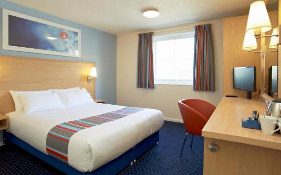 Travelodge hotel room with king size bed and desk.